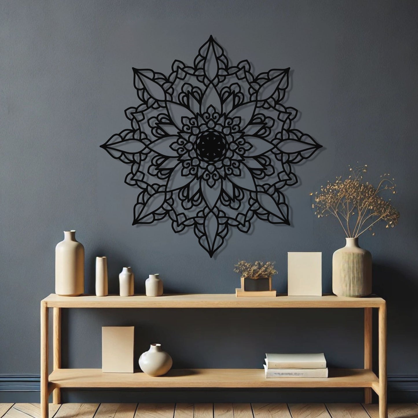 Decorative black mandala wall art on a gray wall with a wooden shelf below.