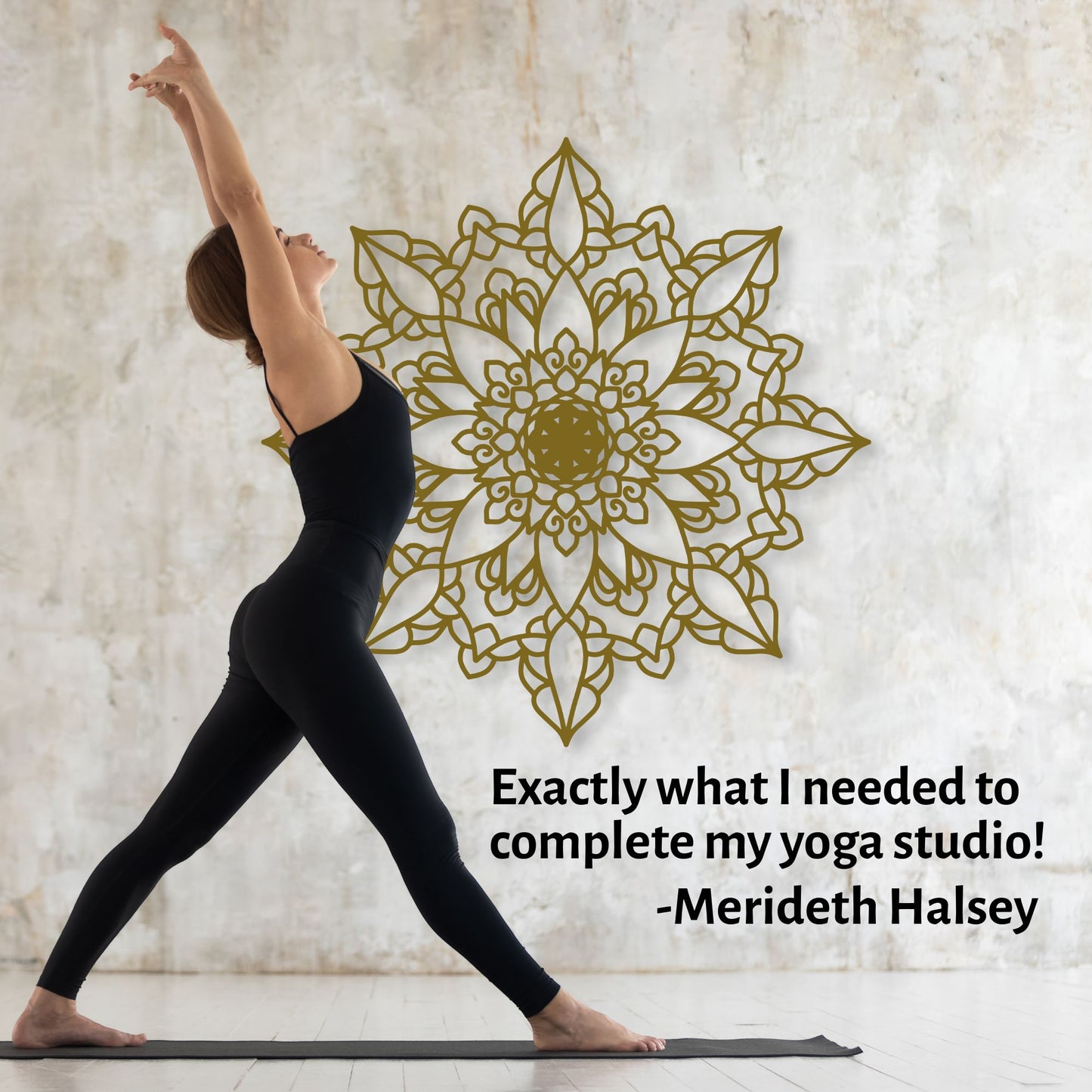 Woman in black yoga attire practicing yoga in front of a decorative wall with a gold mandala design.