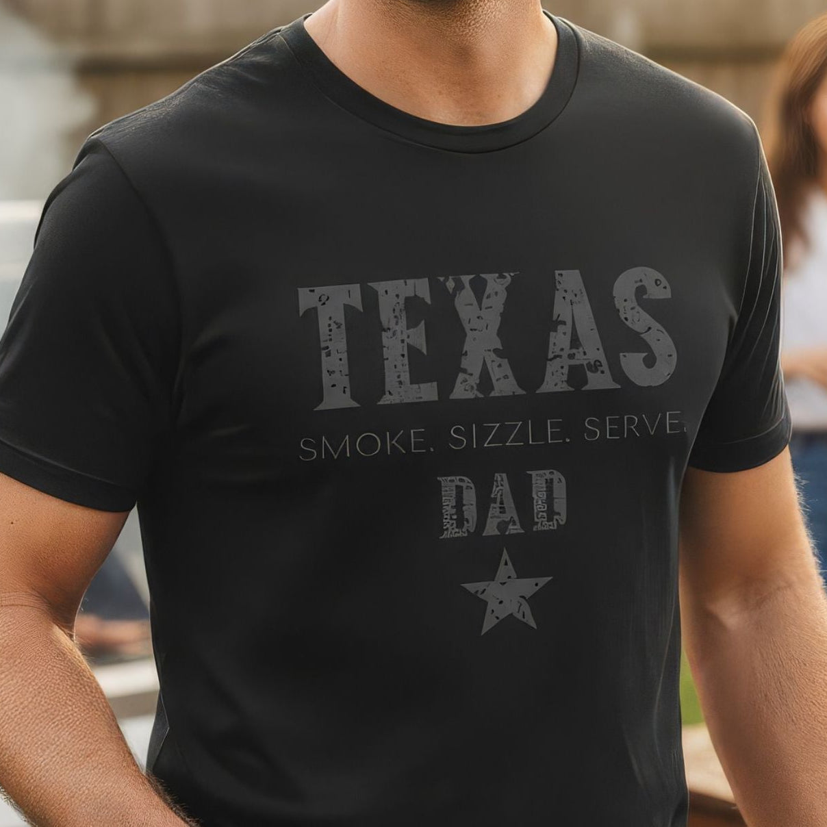 Man wearing a 'Texas Dad' t-shirt at a barbecue with family in the background