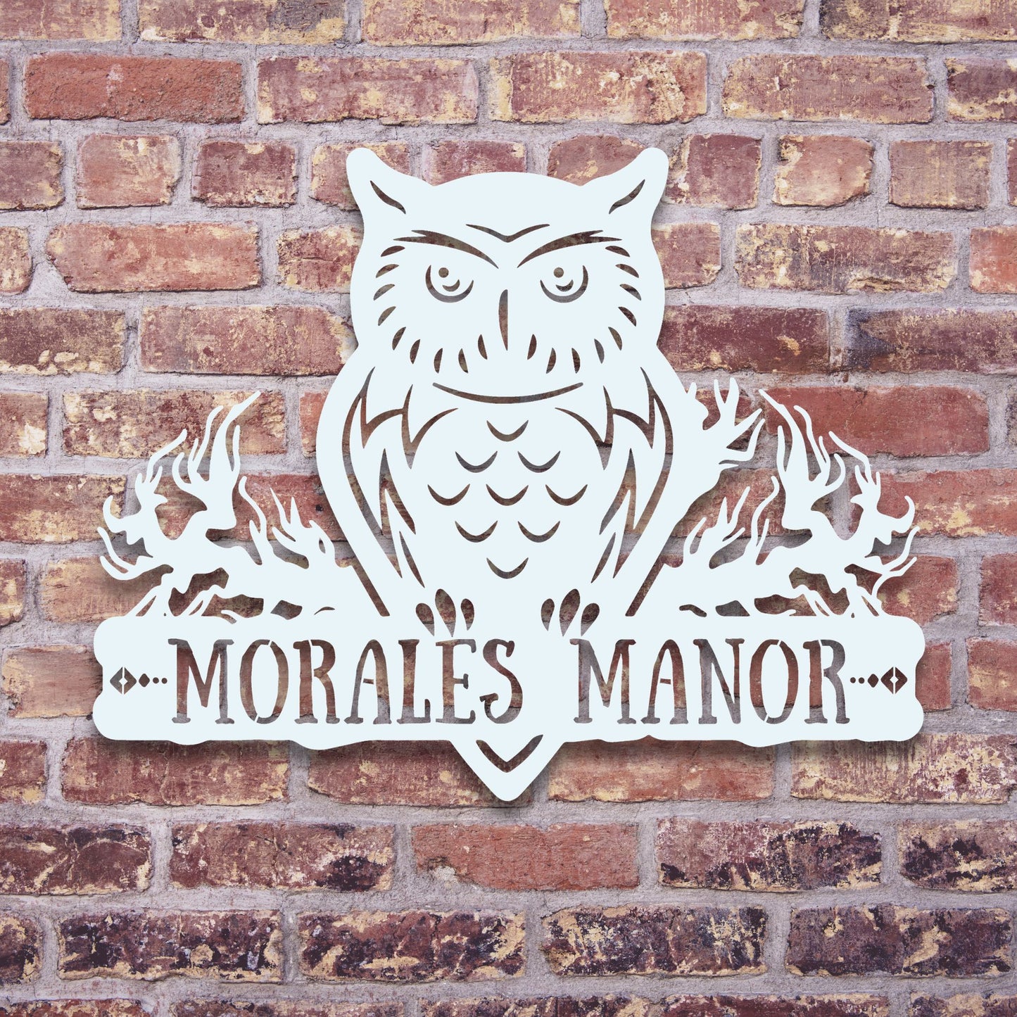 Metal owl sign with 'MORALES MANOR' text on a brick wall