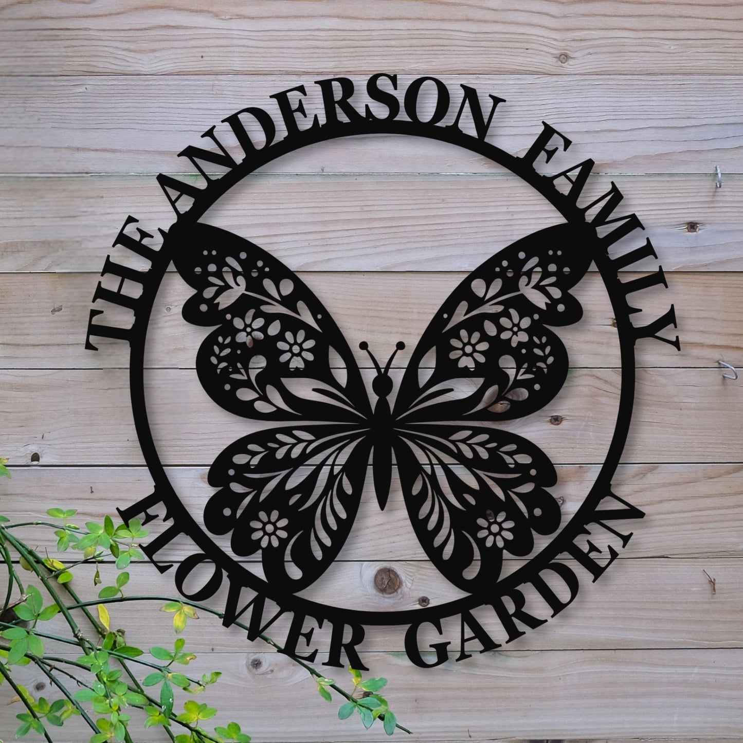 Decorative metal sign with butterfly design and 'The Anderson Family Flower Garden' text on a wooden background.