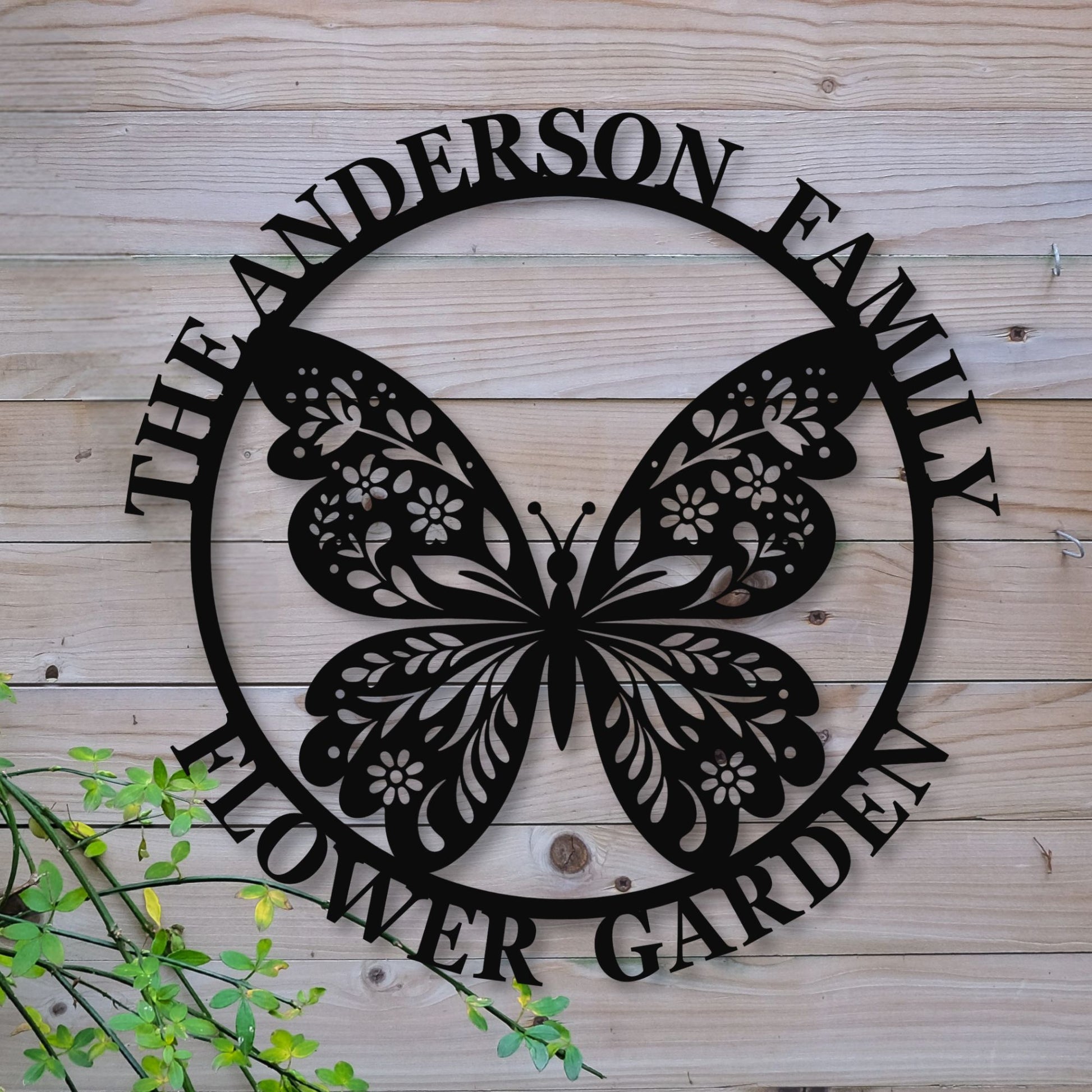 Decorative metal sign with butterfly design and 'The Anderson Family Flower Garden' text on a wooden background.