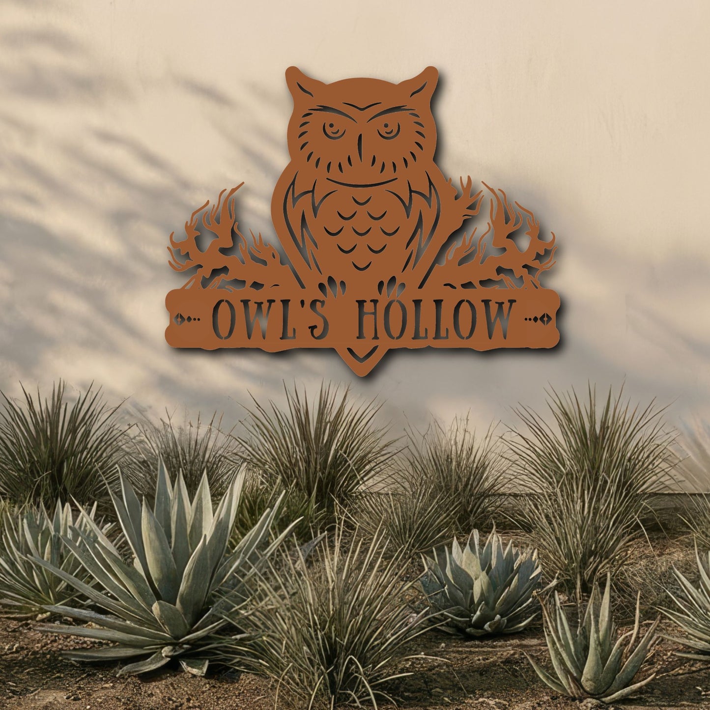 Decorative metal owl sign with 'OWL'S HOLLOW' text in a desert landscape.