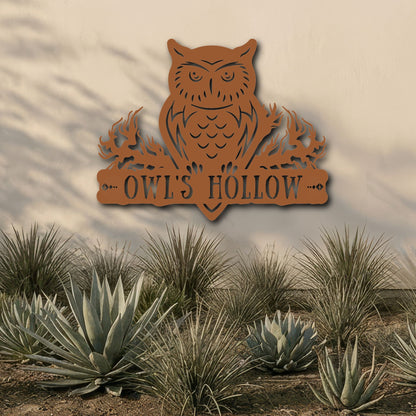 Decorative metal owl sign with 'OWL'S HOLLOW' text in a desert landscape.