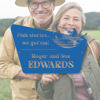 Two people holding a blue sign with text and a fish illustration, standing outdoors.