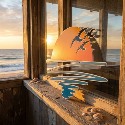 Decorative painted sunset art by a window with a view of the ocean at sunset.