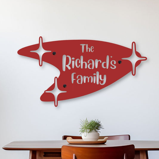 Dining room with a red family name wall art above a wooden table and chairs.