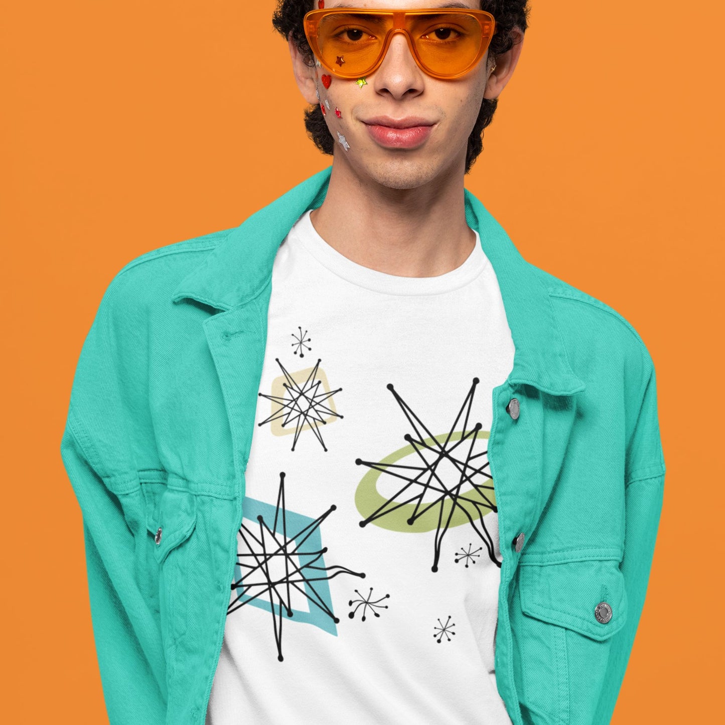Person wearing a turquoise jacket and white t-shirt with star designs on an orange background