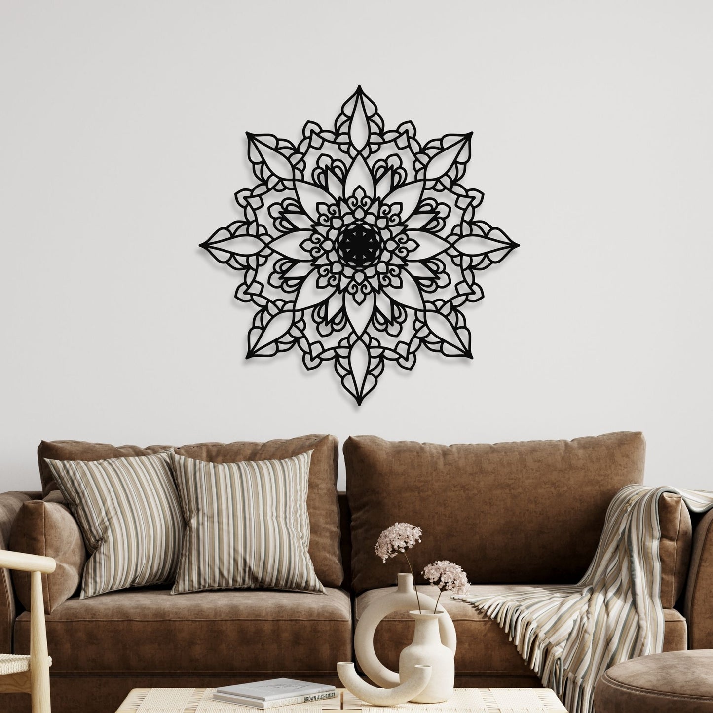 Decorative black mandala wall art above a brown sofa with pillows and a vase.