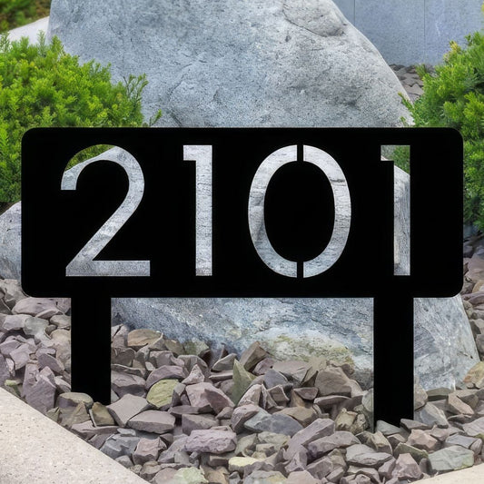 House number sign '2101' on a garden path with rocks and plants.