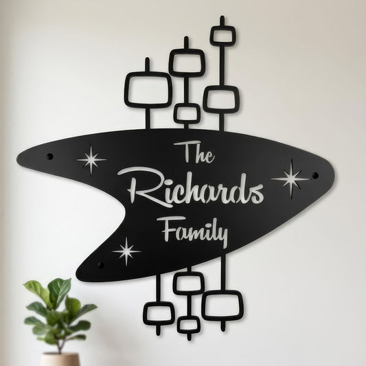 retro boomerang name sign with the richards family die cut into metal hanging in mid century modern room by window